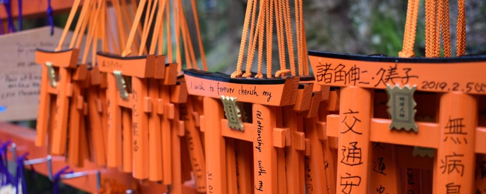 京都伏见稻荷大社千本鸟居清晨景象，朱红色鸟居在晨雾中绵延排列，前往京都的旅行者在鸟居隧道中穿行，画面神圣静谧